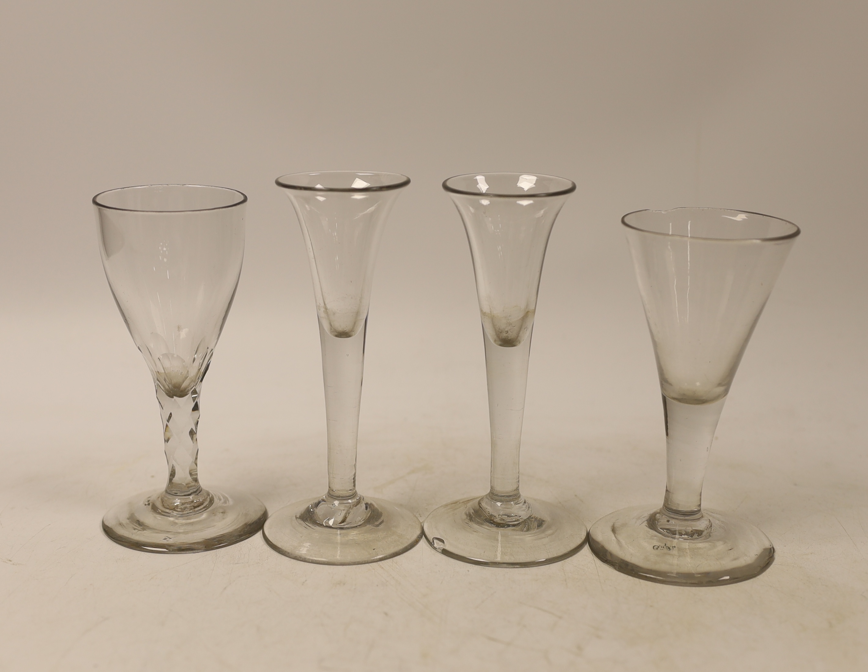 Three mid-18th century drawn trumpet drinking glasses, and a facet stem glass, tallest 13cm (4)